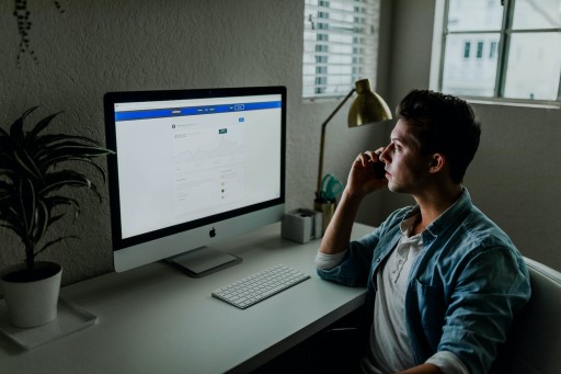 E-commerce: man in blue denim jacket facing turned on monitor