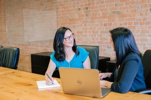 Business Consulting: woman in teal t-shirt sitting beside woman in suit jacket